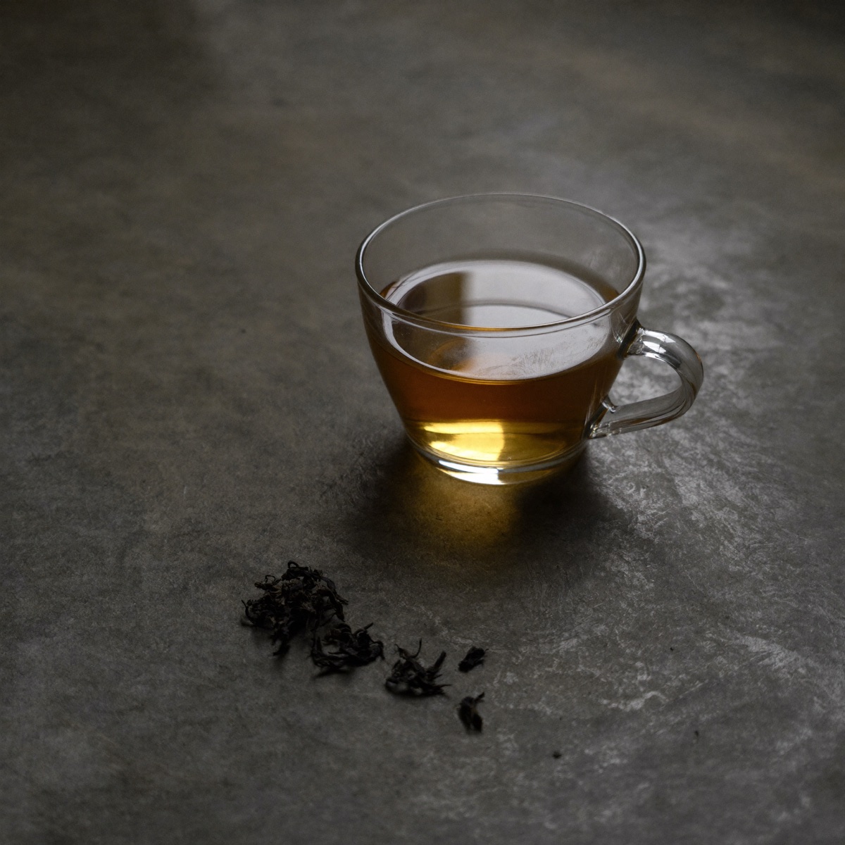 Tazza di te nero Darjeeling in vetro con foglie infuse