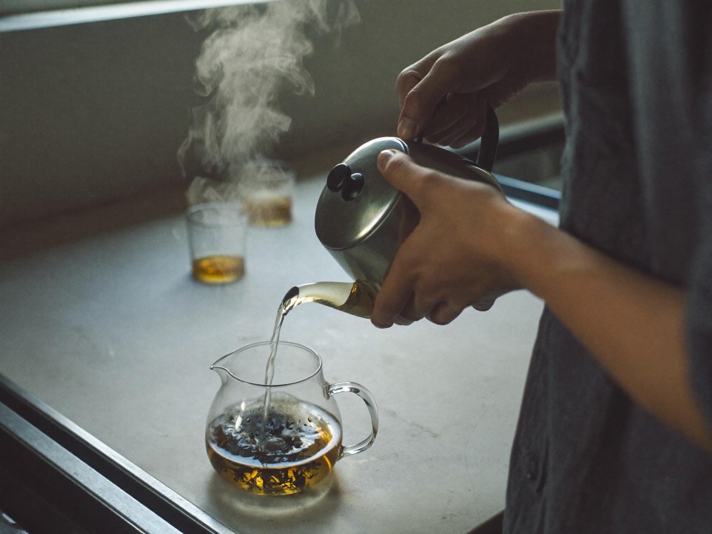 Infusione di te in foglia in una teiera di vetro accanto a barattoli di latta