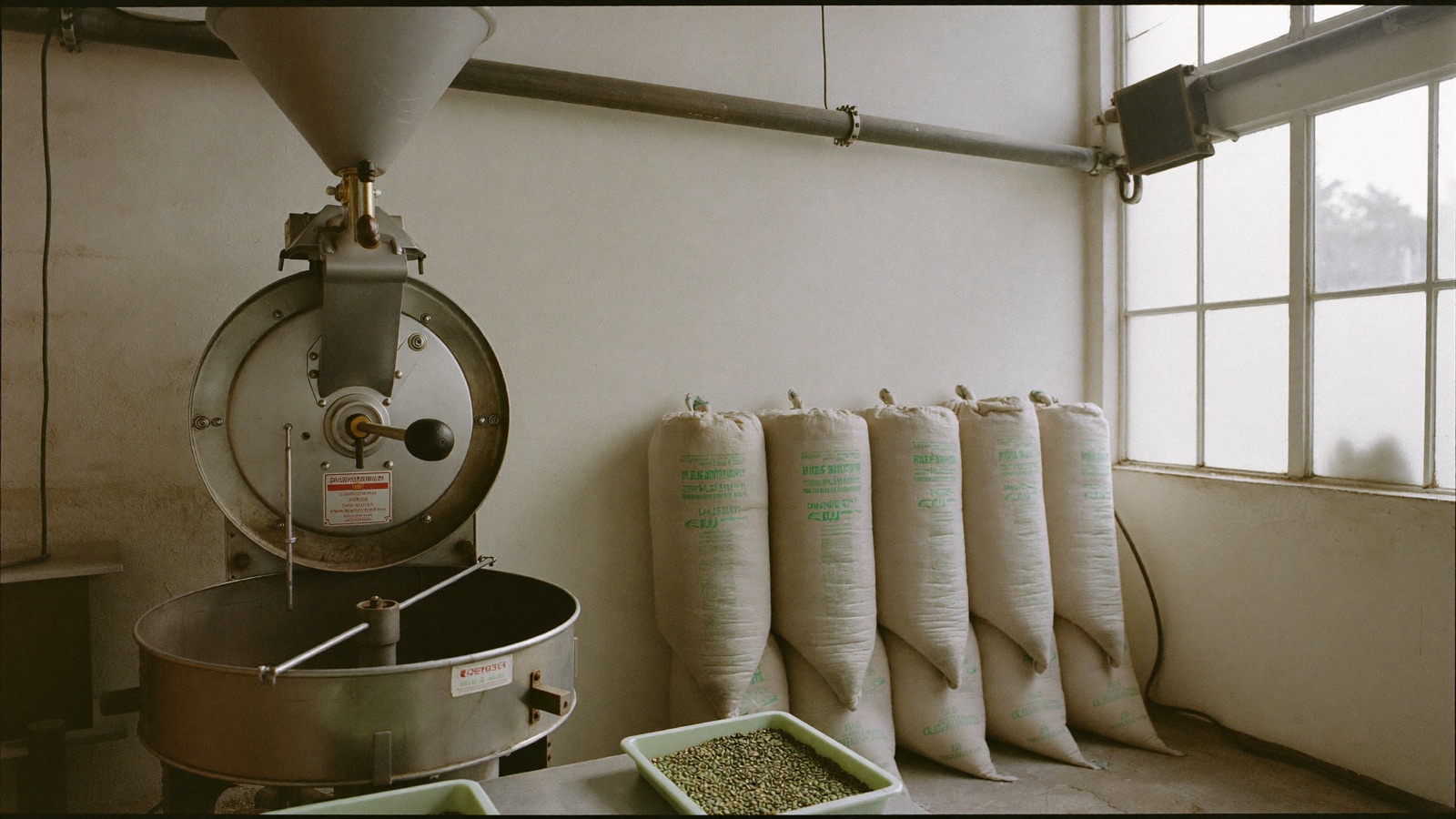 Tostatrice a tamburo in un laboratorio milanese con sacchi di caffe verde